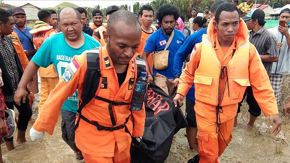 National Search And Rescue Agency personnel and police carry the body of flood victim at Sentani. [BASARNAS via AP]