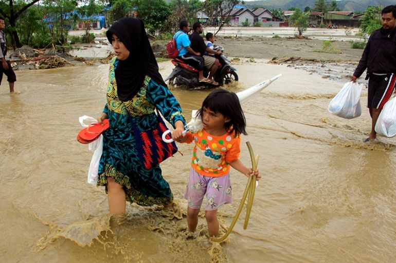 Residents carry their belongings as they wade through flood water in Sentani, near Jayapura, Papua province, Indonesia, 18 March 2019. At least 79 people were killed and 43 missing as a flash floods h