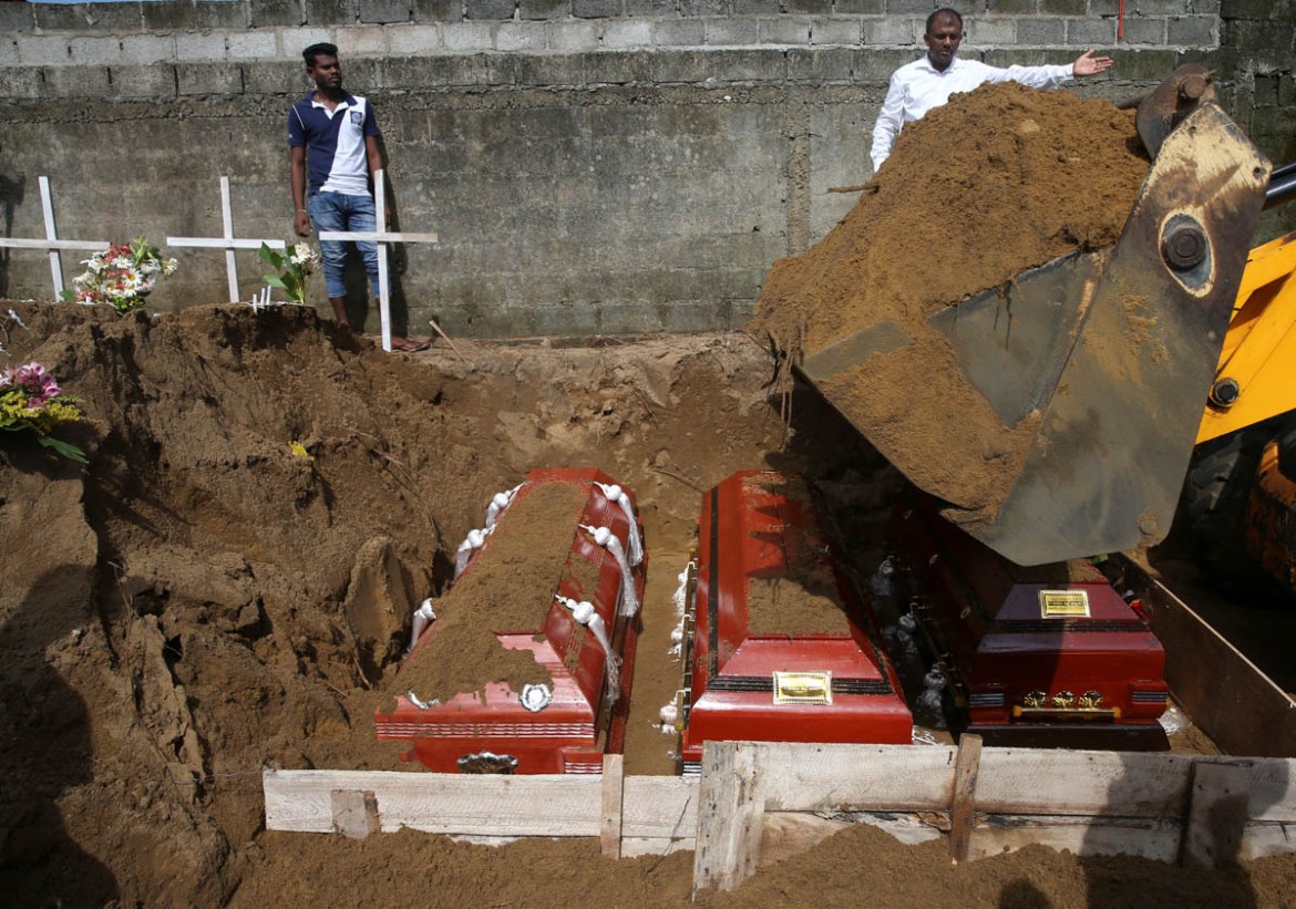 Men coordinate a mass burial of victims, two days after a string of suicide bomb attacks on churches and luxury hotels across the island on Easter Sunday, at a cemetery near St. Sebastian Church in Ne