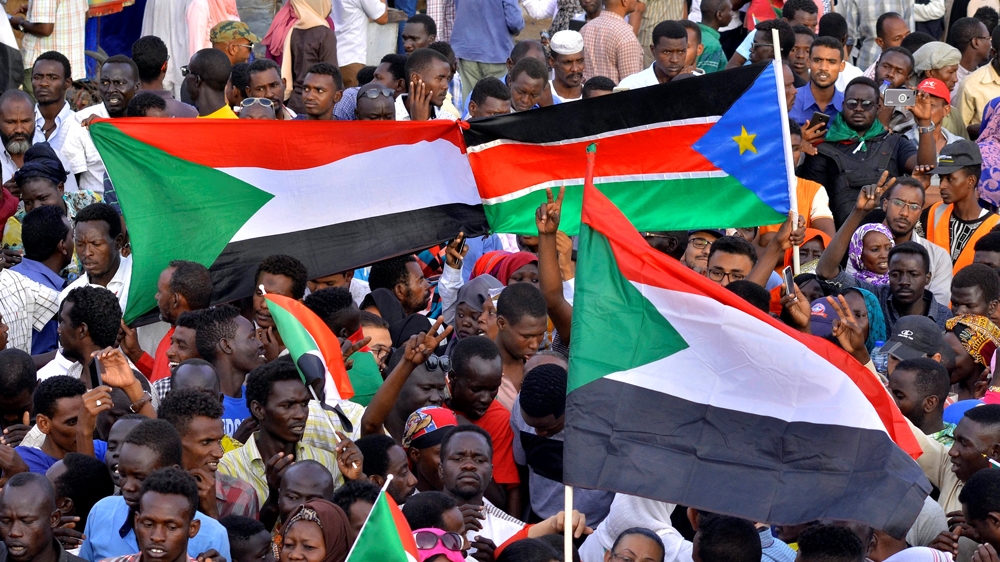 Sudanese demonstrators display their national flag and the national flag of South Sudan, as they attended a sit-in protest outside the defence ministry in Khartoum [Reuters]