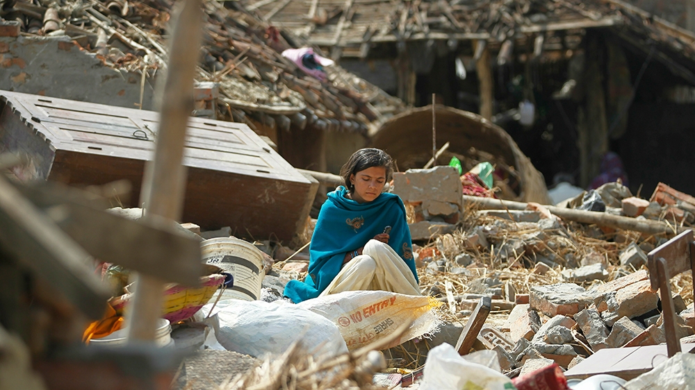A woman sits in the middle of the debris of a house damaged in Bara district [Niranjan Shrestha/The Associated Press]