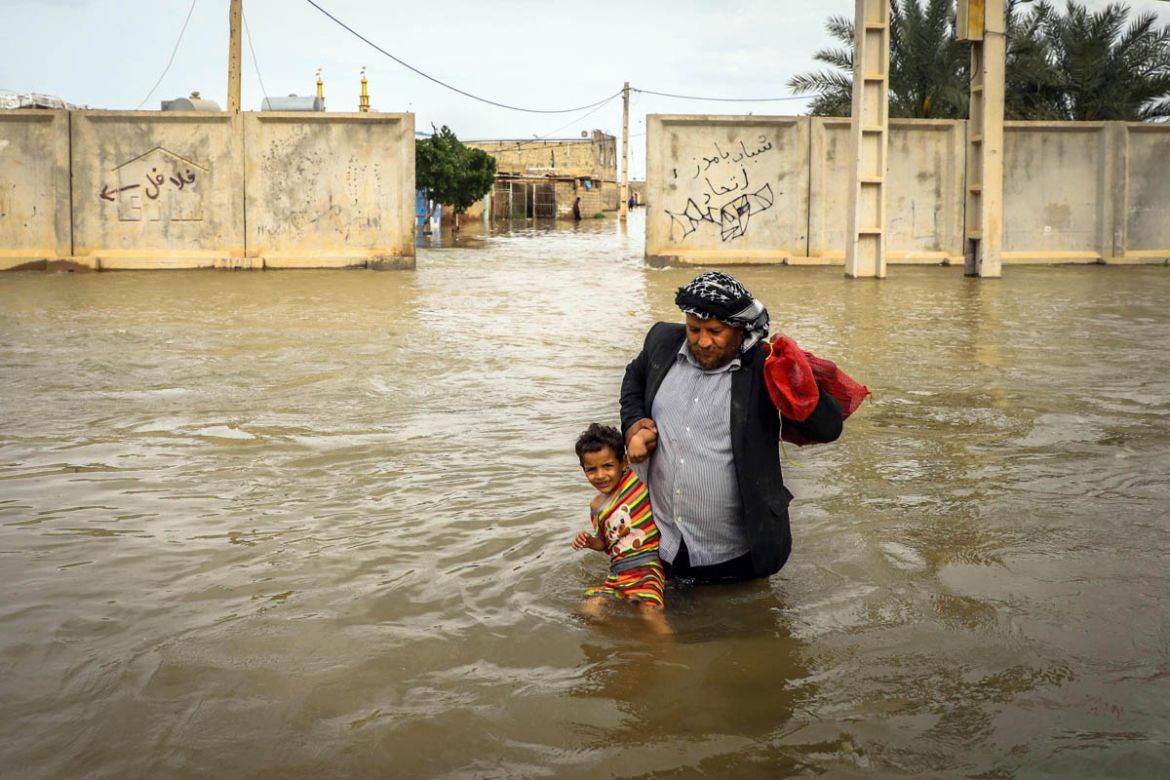 An Iranian man carries his son in a flooded way in a village around t city of Ahvaz, Khuzestan province, Iran, 31 March 2019 (issued 02 April 2019). At least 45 people have died in the past two weeks