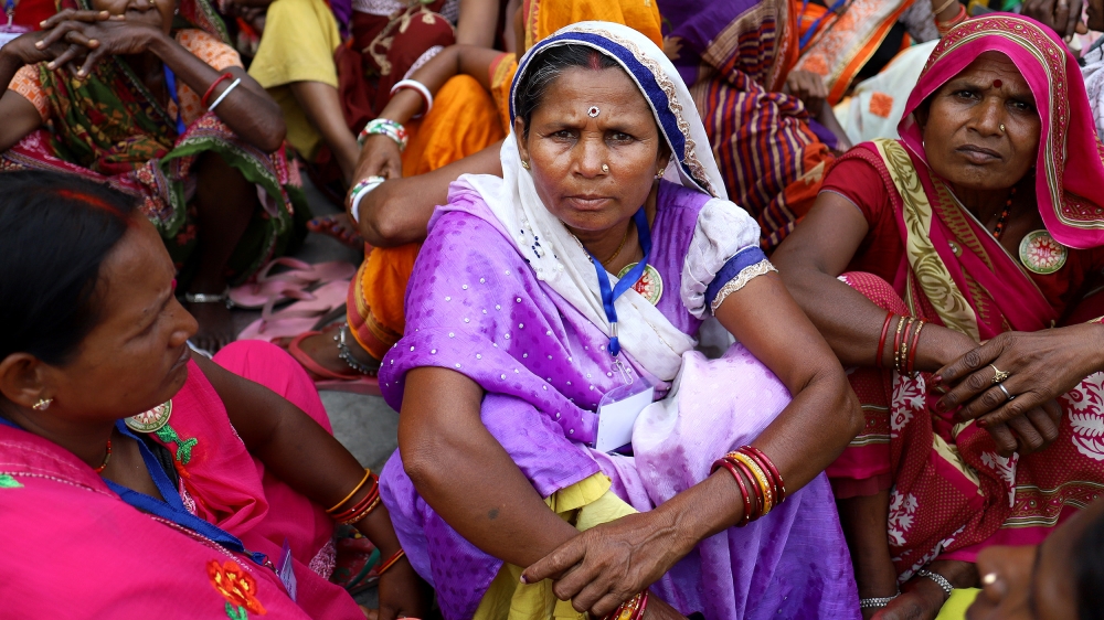 Neelam Devi, who travelled over 1,000km from her village in Bihar to attend the 'People's Agenda' rally at the Talkatora Stadium in New Delhi, organised by civil 300 society groups, waits with other women for her turn to enter the demonstration venue [Vijay Pandey/Al Jazeera]