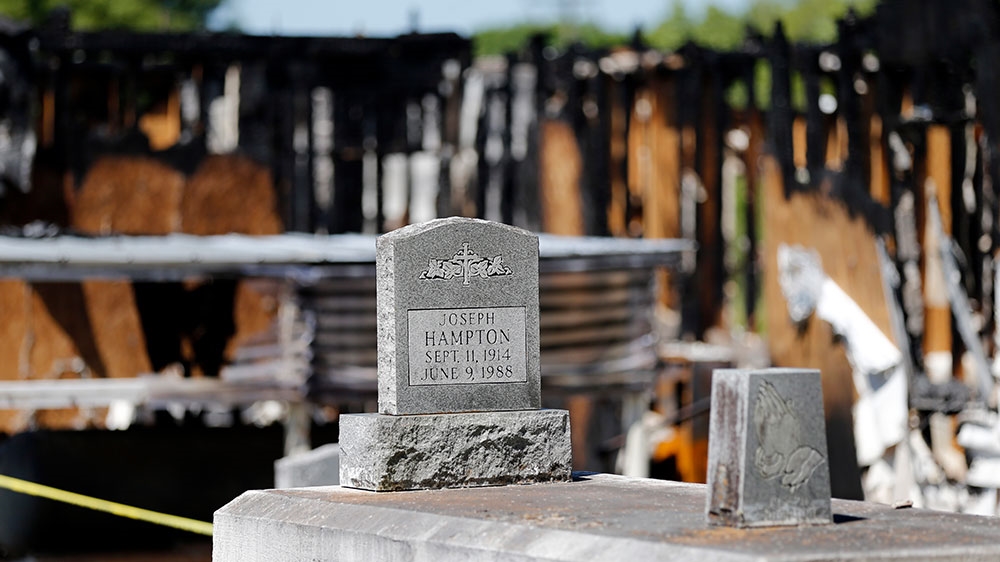 Graves from a cemetery are seen behind the burned ruins of the Greater Union Baptist Church, one of three that recently burned down in St Landry Parish, are seen in Opelousas [Gerald Herbert/AP Photo] 
