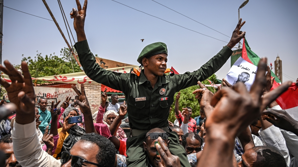 Sudanese protestors shout slogans as they carry a sudanese officer during a protest outside the army complex [Ozan Kose/ AFP]
