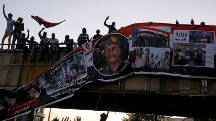 Protesters tear down a banner with a picture of Sudan''s head of transitional council, Lieutenant General Abdel Fattah Al-Burhan Abdelrahman and pictures showing the Sudanese soldiers and protesters to