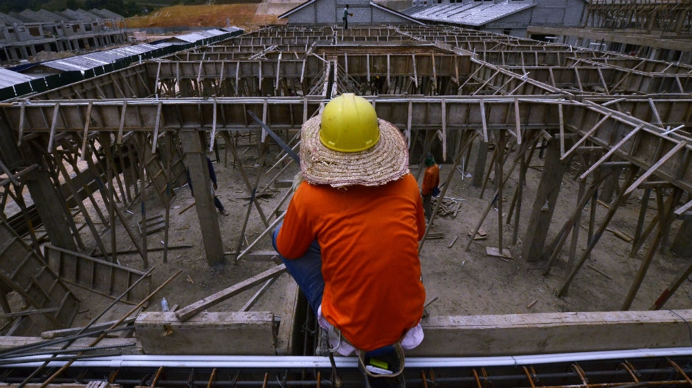 A construction worker rests on a rooftop at a housing construction project in Kuala Lumpur. [Samsul Said/Reuters]