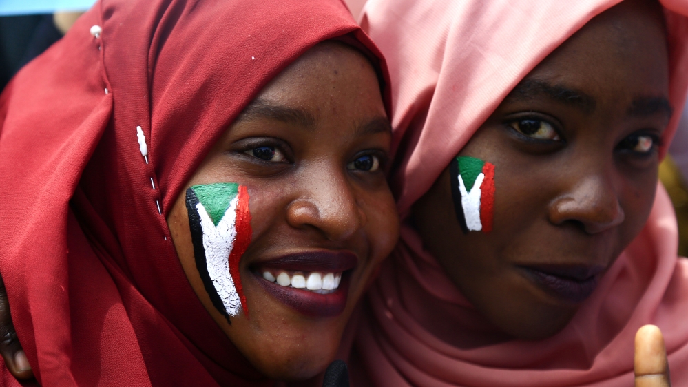 Sudanese women with national flags painted on their faces take part in a rally near the military headquarters in Khartoum [Ashraf Shazly/AFP]