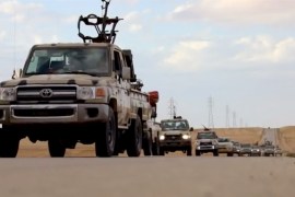 Pickup trucks with mounted weapons drive on a road in Libya