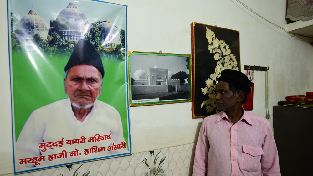 Iqbal with a portrait of his late father, Hashim Ansari, the main litigant in the Ayodhya dispute [Amar Deep Sharma/Al Jazeera]
