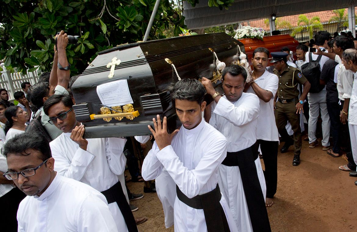 Clergymen carry coffins for burial during a funeral service for Easter Sunday bomb blast victims at St. Sebastian Church in Negombo, Sri Lanka, Tuesday, April 23, 2019. (AP Photo/Gemunu Amarasinghe)