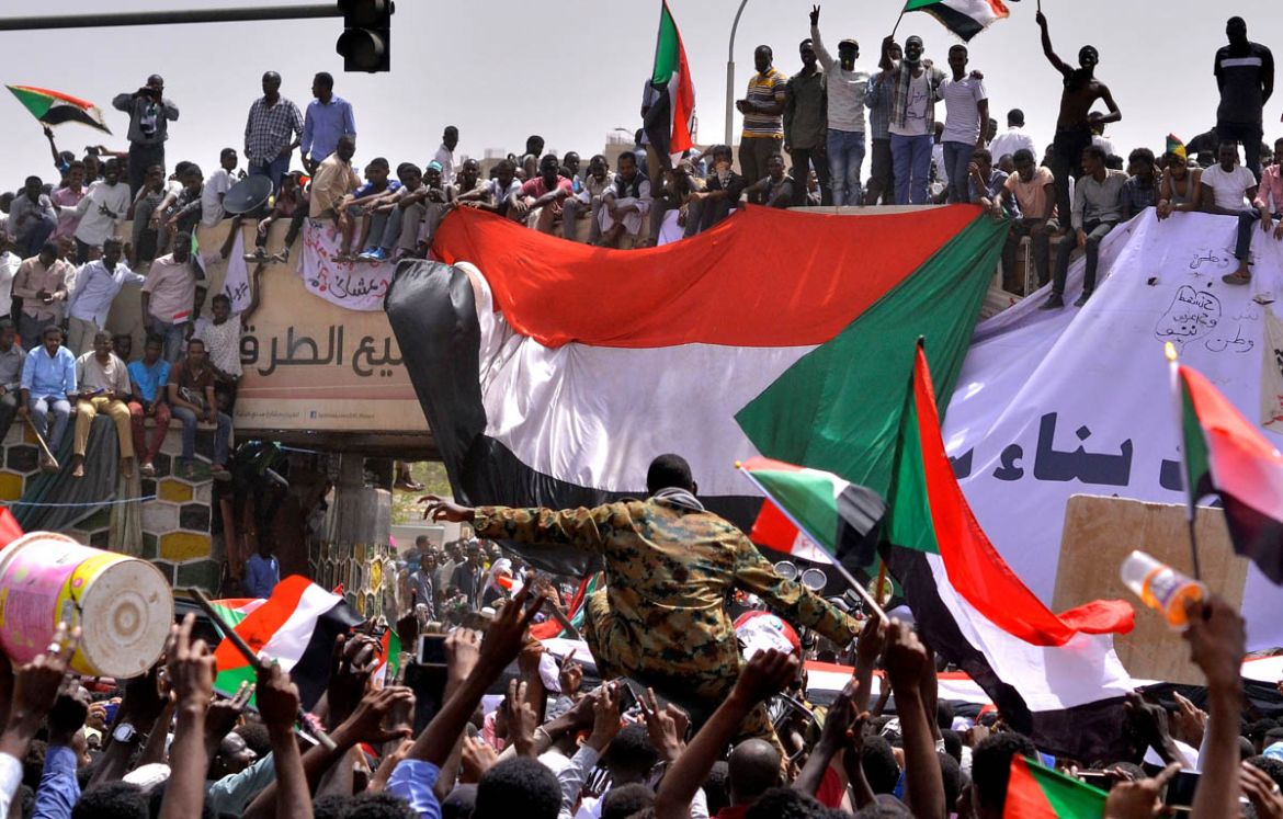 A military officer is carried by the crowd as demonstrators chant slogans and carry their national flags, after Sudan''s Defense Minister said that President Omar al-Bashir had been detained ''in a safe