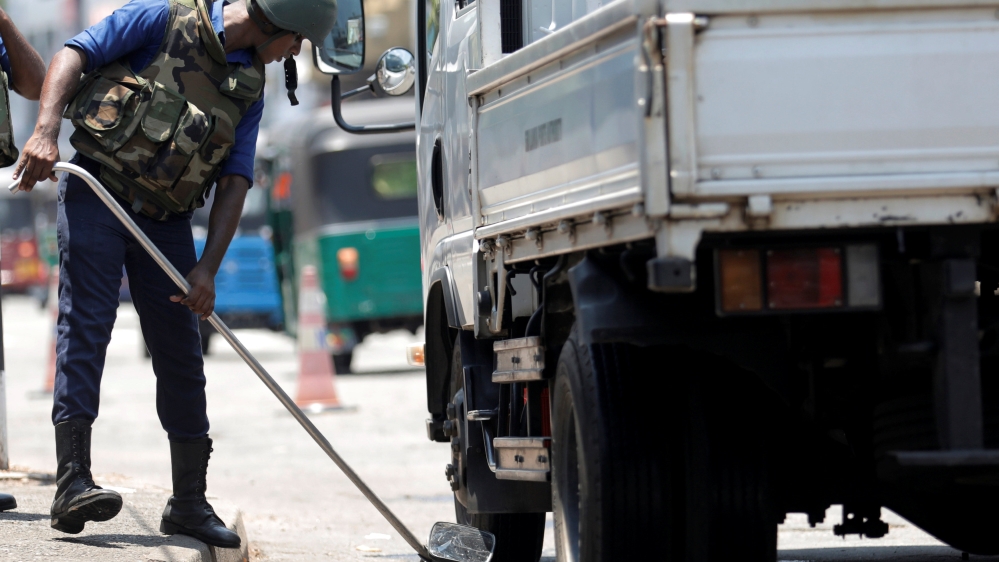 A Sri Lankan navy soldier searches a truck at a check point in Colombo [Dinuka Liyanawatte/Reuters]