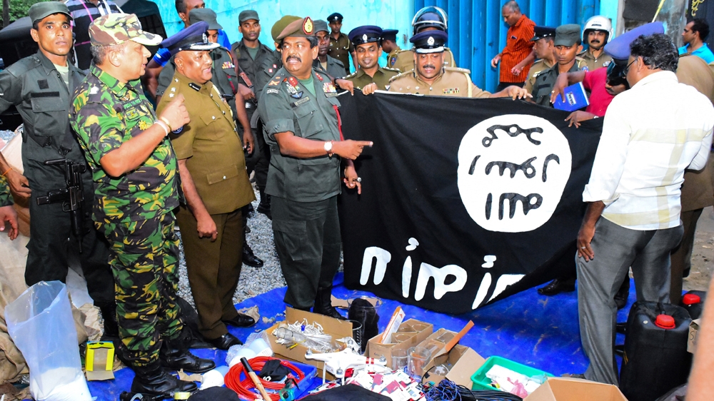 Sri Lanka's security personnel hold up an ISIL flag discovered in a safe-house in the eastern town of Kalmunai [AFP]