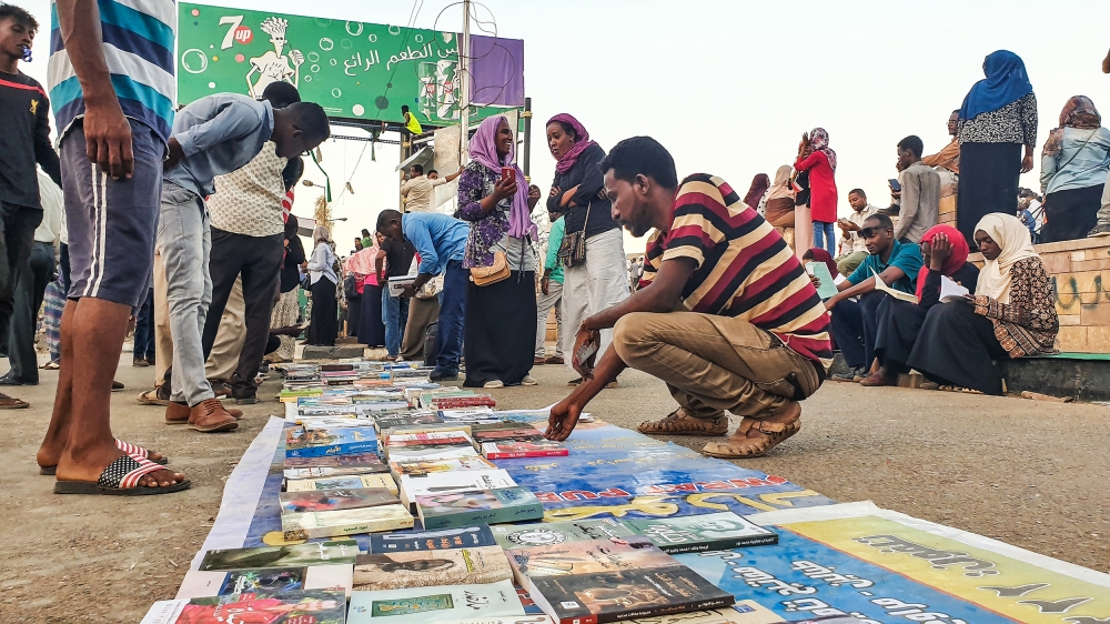 The open-air library has no shelves or stands with books spread in straight lines on the tarmac [Hamza Mohamed/Al Jazeera]