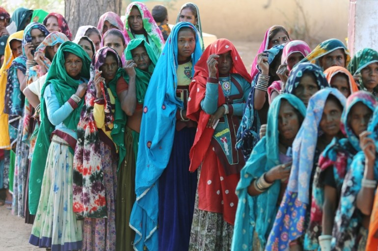 Women wait in a queue to cast their vote at a polling station at Sirohi, India elections