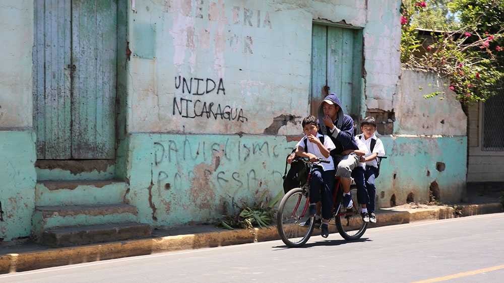 A Nicaraguan family cycles on street outside of Masaya, Nicaragua, where the government's violent crackdown on anti-government protests last year left a city divided by opponents and supporters of President Daniel Ortega [Chris Kenning/Al Jazeera]