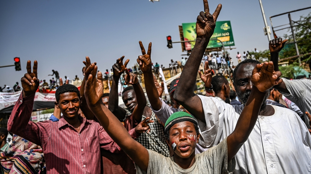Sudanese protesters chant slogans and flash victory signs as they continue to protest outside the army complex in Khartoum [Ozan Kose/AFP]