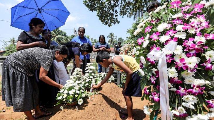 Family put flowers on the grave of Rexy Duglas, 67, three days after a string of suicide bomb attacks on churches and luxury hotels across the island on Easter Sunday, at a cemetery near St Sebastian'