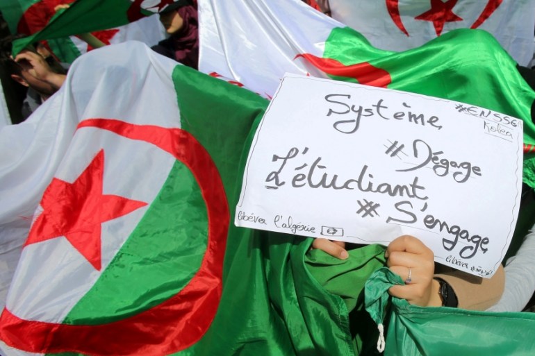 Demonstrators hold flags and banners during anti government protests in Algiers