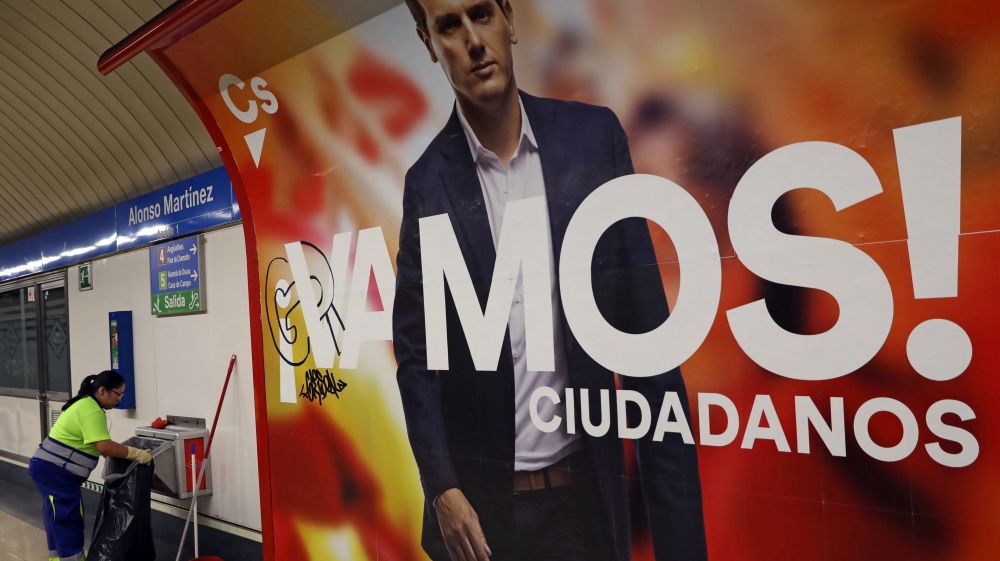 A worker empties trash cans next to an electoral poster of Ciudadanos' candidate Albert Rivera in a metro station in Madrid, Spain [Susana Vera/Reuters]
