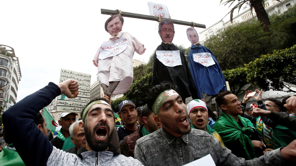 Protesters carry a mock hangman with the faces of businessman Ali Haddad, former PM Ahmed Ouyahia and Said Bouteflika, the ex-president's brother [Ramzi Boudina/Reuters]