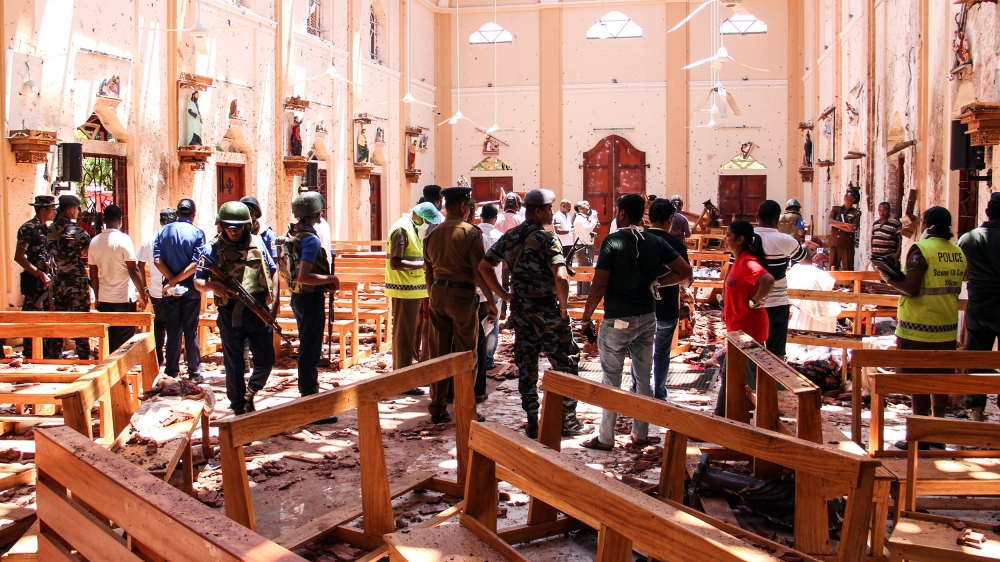 Sri Lankan security personnel walk through debris following an explosion in St Sebastian's Church in Negombo, north of the capital, Colombo [AFP]
