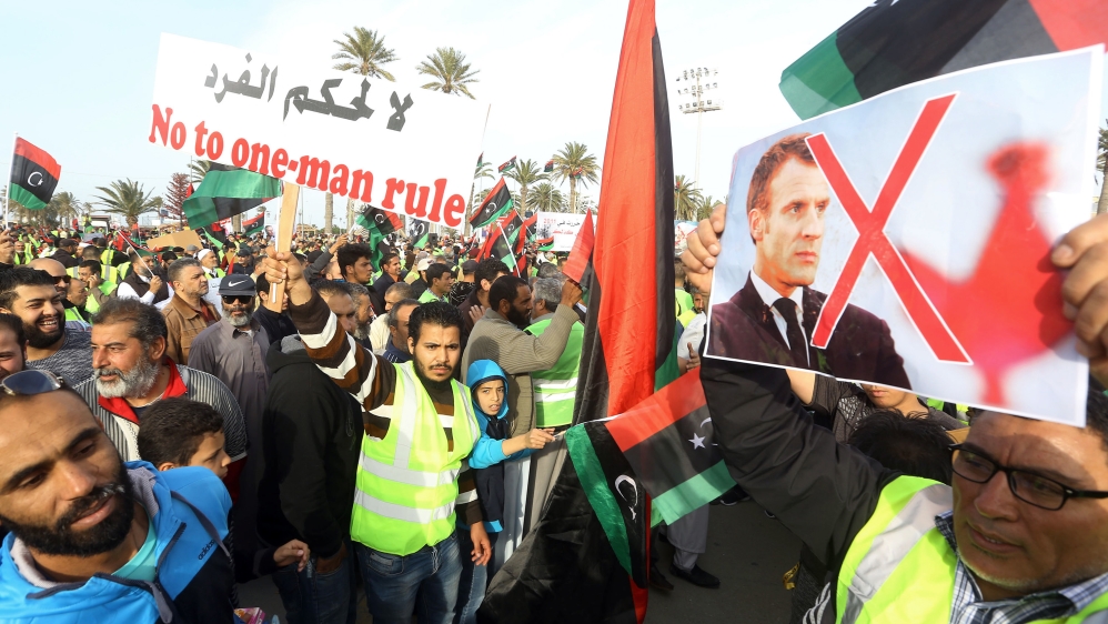 Libyan protesters carry a portrait of French President Emmanuel Macron during a demonstration against Haftar in Tripoli [Mahmud Turkia/AFP]
