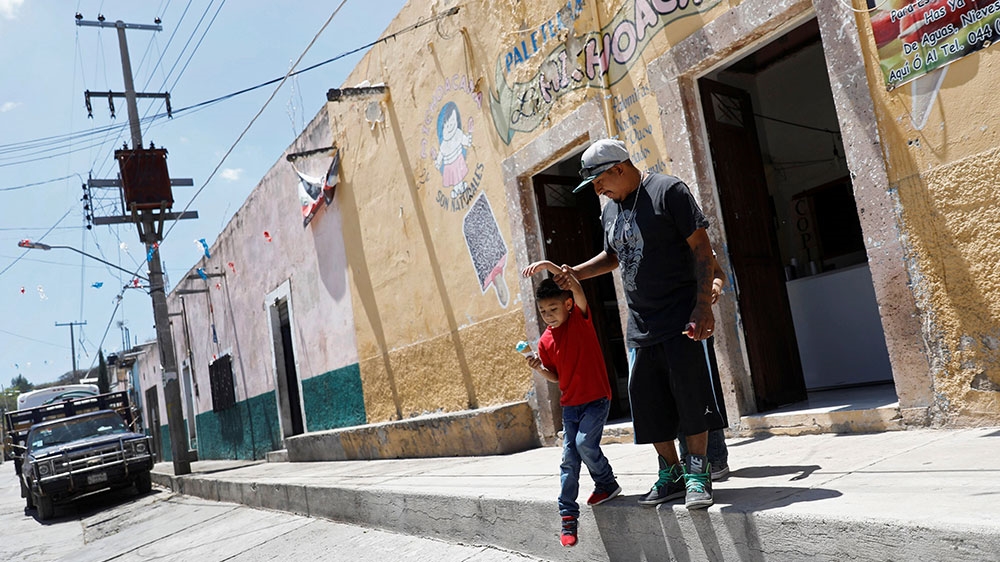 Balbino leaves an ice cream shop with his son Javen, 6, in Neutla, Guanajuato state, Mexico [Edgard Garrido/Reuters] 