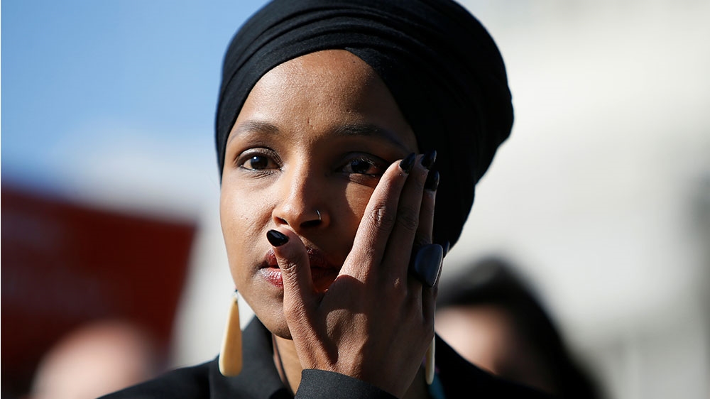 Ilhan Omar wipes tears from her eye as she speaks about Trump administration policies towards Muslim immigrants at a news conference by members of the US Congress [Jim Bourg/Reuters]