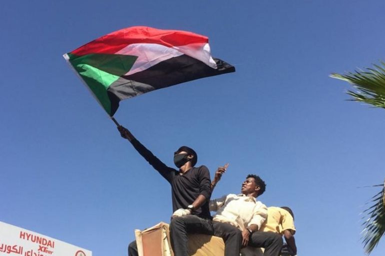 A Sudanese protester waves the national flag as they rally for a second day outside the military headquarters in the capital Khartoum on April 7, 2019. - Sudanese police fired tear gas at thousands of