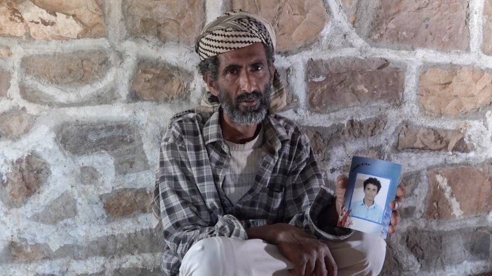 
Ali Hameed holds a picture of his 15-year-old son, Mohammad, who has been missing since he left to join the Saudi-UAE-led coalition [Al Jazeera]
