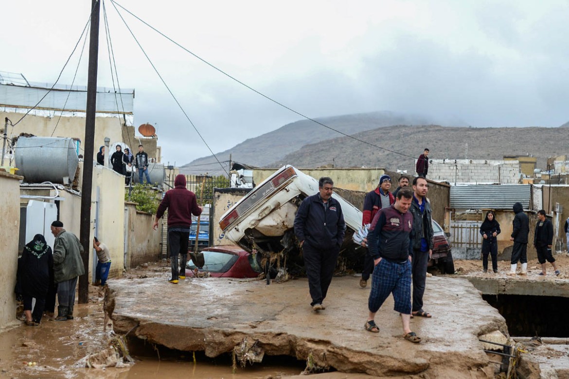 People walk next to damaged vehicles after a flash flooding in Shiraz, Iran, March 26, 2019. Tasnim News Agency/via REUTERS ATTENTION EDITORS - THIS PICTURE WAS PROVIDED BY A THIRD PARTY