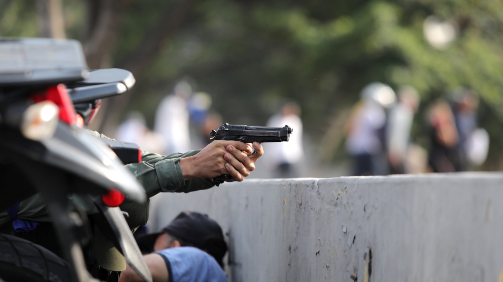 A military member aims a gun near the Generalisimo Francisco de Miranda Airbase, La Carlota [Manaure Quintero/Reuters]