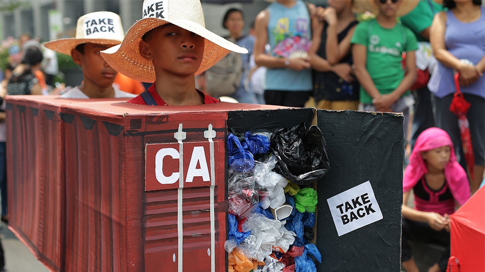 Filipino environmental activists wear a mock container vans filled with rubbish to symbolize the 50 containers of waste that were shipped from Canada to the Philippines [File: Aaron Favila/AP Photo] 