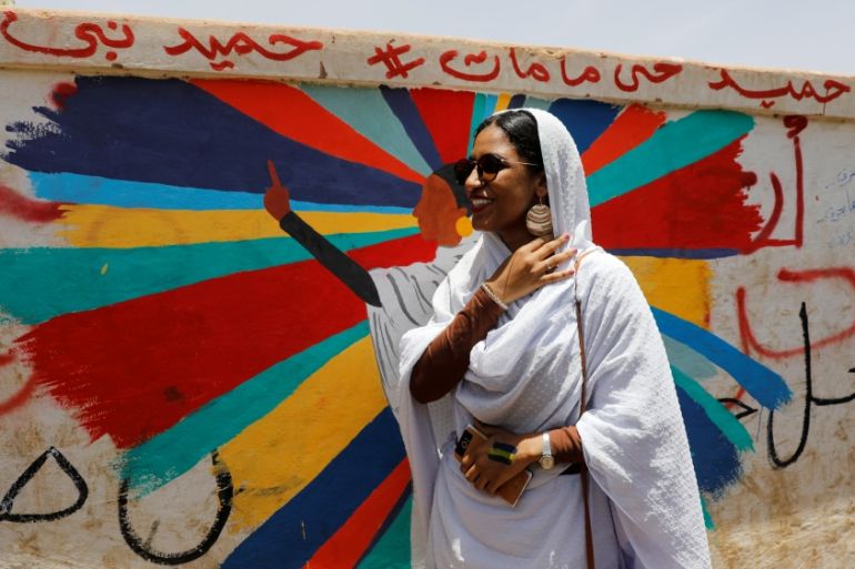 Alaa Salah, a Sudanese protester whose video gone viral and make her an icon for the mass anti-government protests, stands in front of a mural depicting her in front of the Defence Ministry, Khartoum