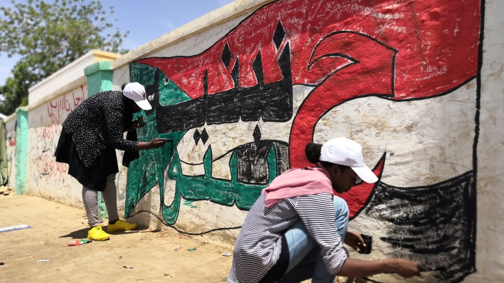 Young Sudanese paint a national flag on a wall in the capital Khartoum [Ashraf Shazly/AFP]