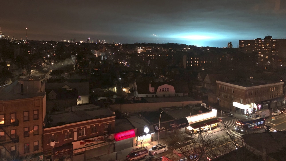The sky above a Consolidated Edison power facility in the Astoria neighbourhood of Queens is illuminated with a pulsing blue light from a transformer explosion [Barbara Woike/AP]