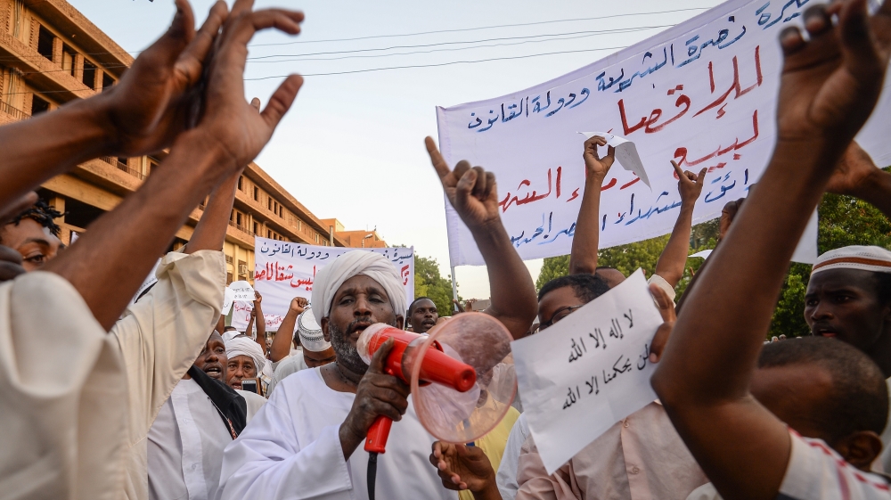 Supporters of Sudanese Islamist movements shout slogans as they rally in front of the Presidential Palace in downtown Khartoum [Mohamed El-Shahed/AFP]