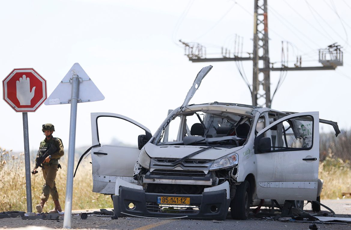 Israeli soldier walks past a car hit by a missile fired from Gaza near the Gaza and Israel border, Sunday, May 5, 2019. Palestinian militants on Saturday fired over 200 rockets into Israel, drawing do