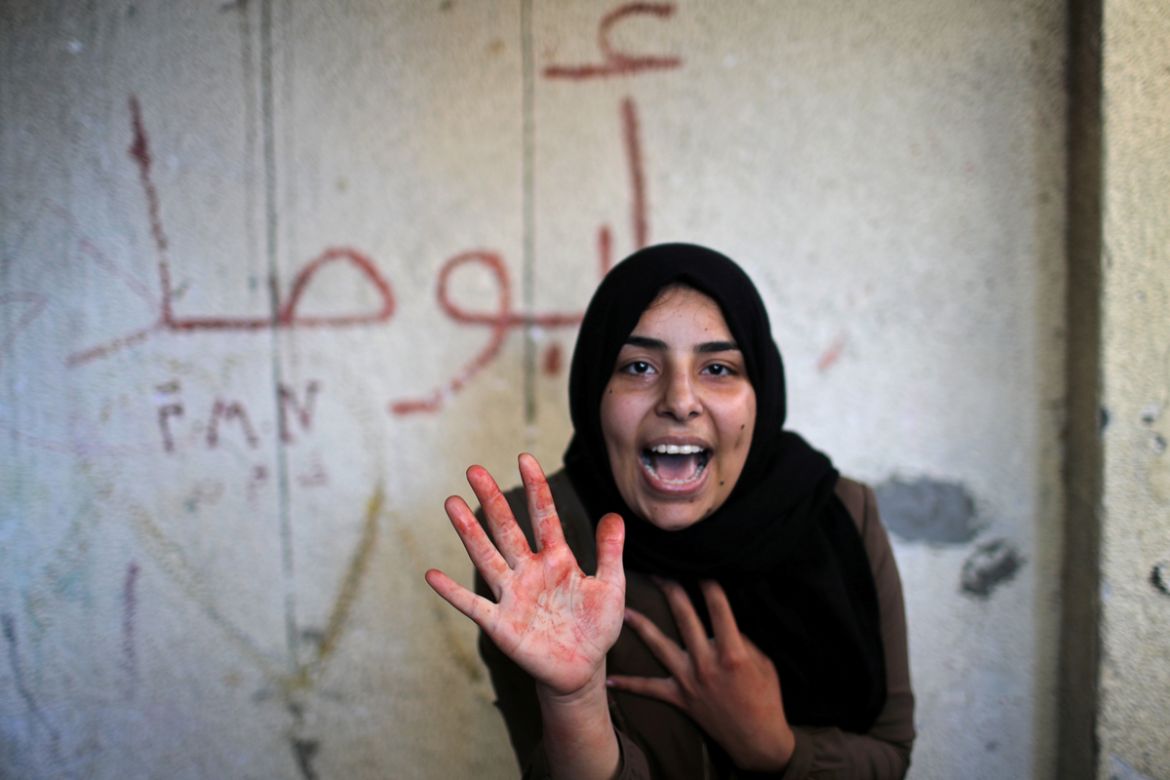 The sister of Palestinian militant Emad Naseer, who was killed in an Israeli air strike, reacts with her hand stained with his blood, during his funeral in the northern Gaza Strip May 4, 2019. REUTERS