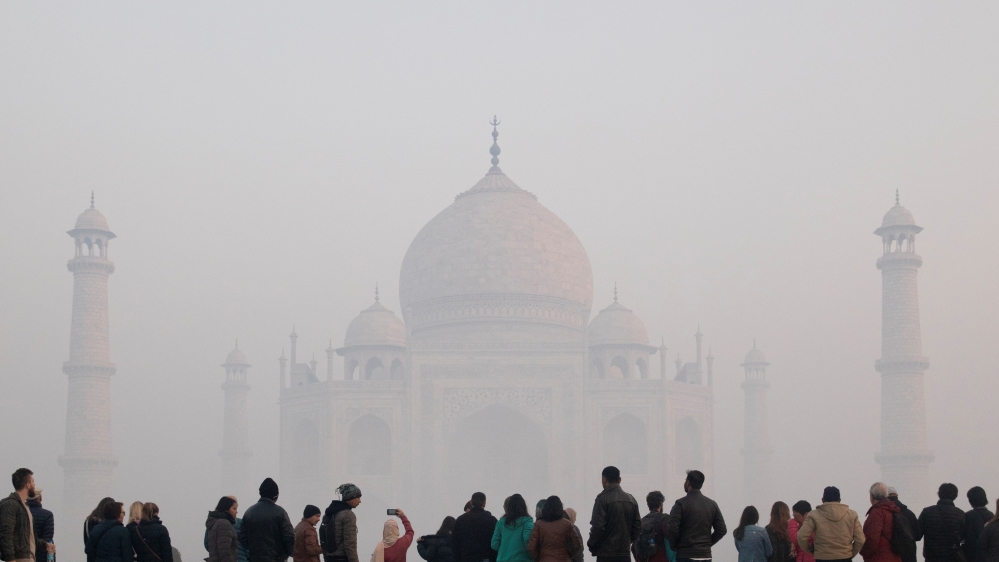 Visitors look toward the Taj Mahal through morning air pollution in Agra