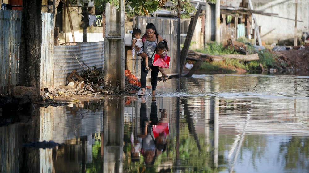 Displaced by floods, Sonia Cardozo, 38, walks by a flooded street as she holds her daughters Milena and Teresa in Asuncion, Paraguay [Jorge Saenz/AP]
