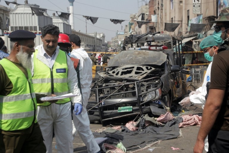 Security officials and members of a bomb disposal team survey the site after a blast in Lahore,