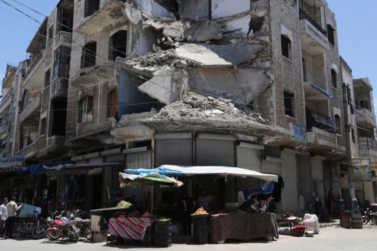 People walk past a damaged building in the city of Idlib