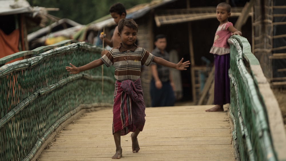 Children cross the bridge build across the canal separating the camp from Bangladesh [Sorin Furcoi/Al Jazeera]