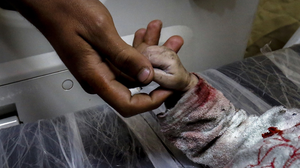 A man holds the hand of Maria al-Gazali, a Palestinian baby, as her body lies on a stretcher at a hospital in Beit Lahia, in northern Gaza strip [Anas Baba/AFP]