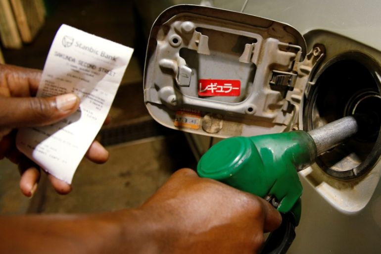 A petrol attendant fuels a car at a filling station in Harare, Zimbabwe