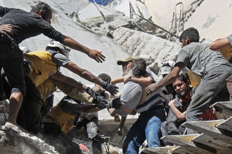 White Helmet rescue volunteers and civilians rescue a child from the rubble of a building destroyed during an air strike by Syrian regime forces and their allies on the town of Ariha, in the southern