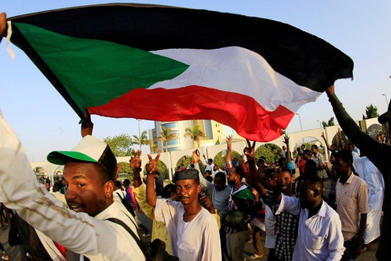 Sudanese protesters carry their national flag as they chant slogans before breaking their fast during the first day of the fasting month of Ramadan